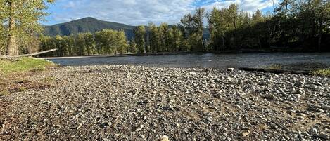 A riverbank with a rocky terrain and a dog in the foreground.