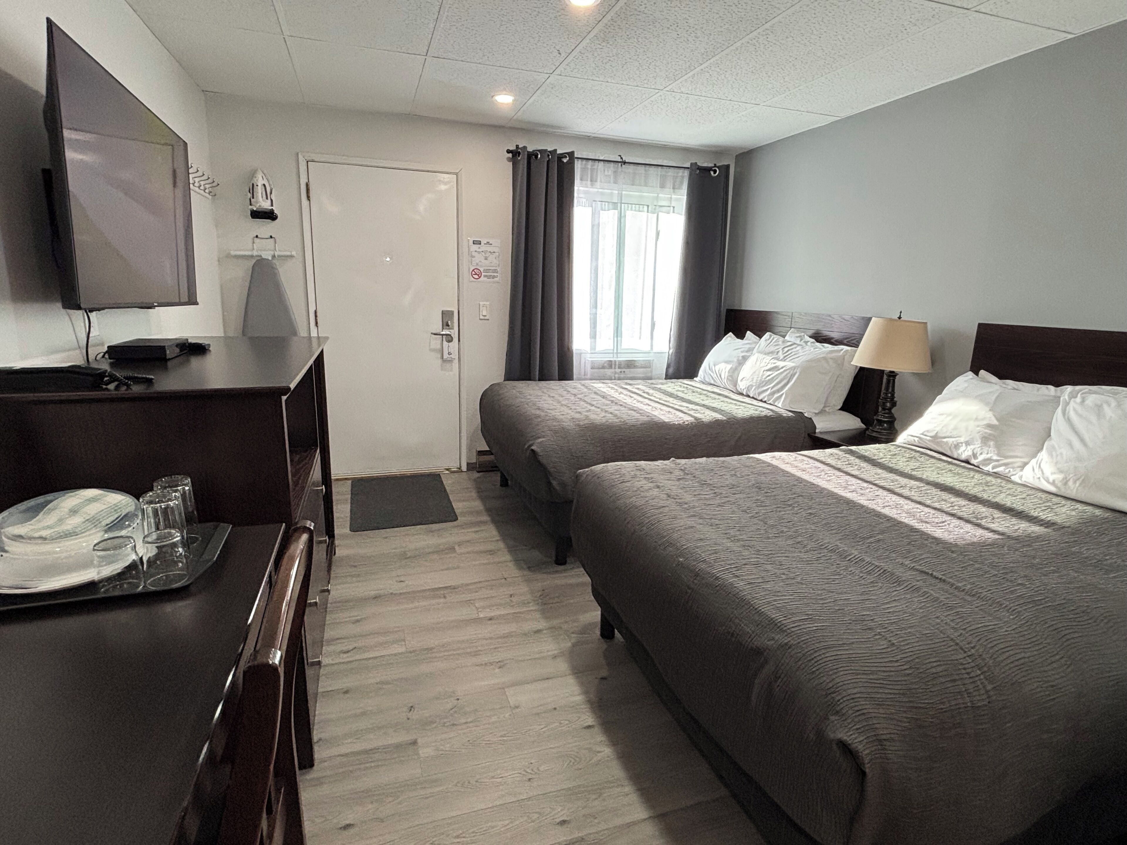 Een hotelkamer met twee bedden, een bureau met televisie en een raam met gordijnen.