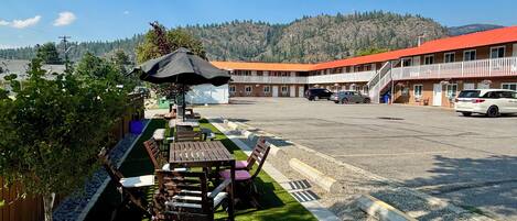 A motel with outdoor seating, a parking lot, and a view of a mountain range.