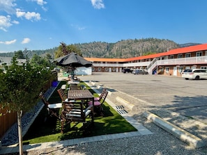A motel with outdoor seating, a parking lot, and a view of a mountain range. - Western Traveller Motel (Grand Forks)