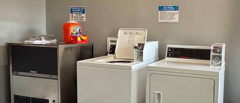 A laundry area with a Tide detergent dispenser, a self-service guest laundry machine, and a sign instructing to use ice scoops for ice removal.