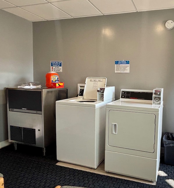 A laundry area with a Tide detergent dispenser, a self-service guest laundry machine, and a sign instructing to use ice scoops for ice removal.