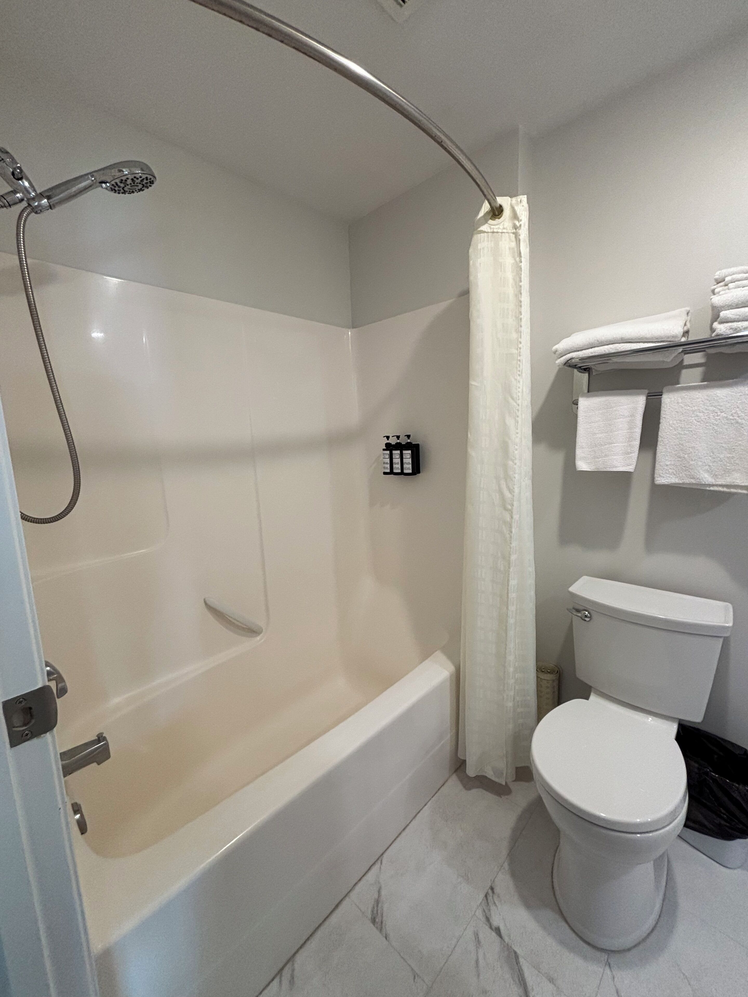 Un baño con bañera, ducha, inodoro y un perchero para toallas.