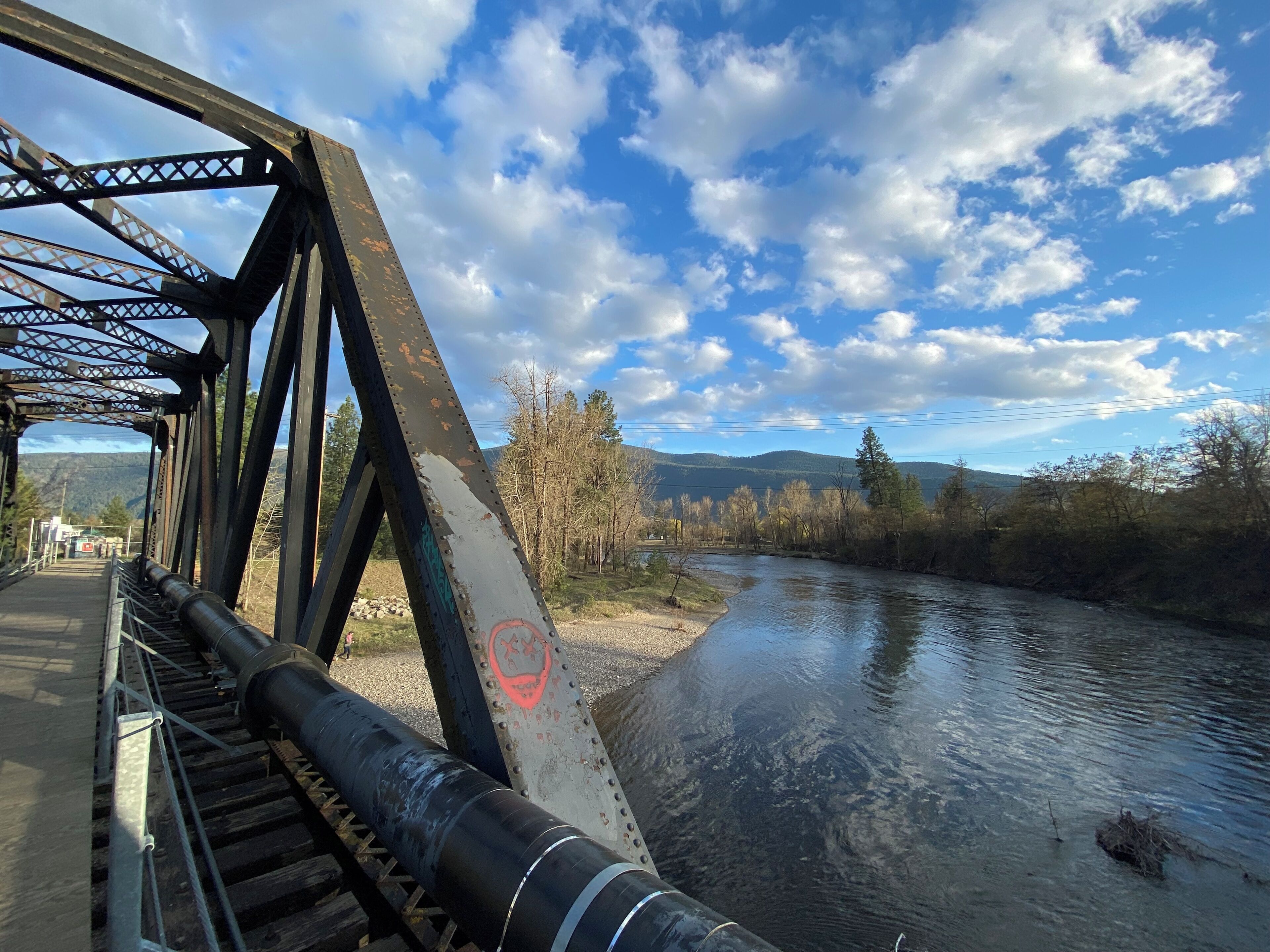 Un pont à structure métallique, avec une rivière en contrebas.