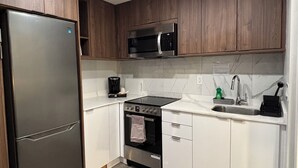 A modern kitchen with a stainless steel refrigerator, a microwave, an oven, and a sink. - Western Traveller Motel (Grand Forks)