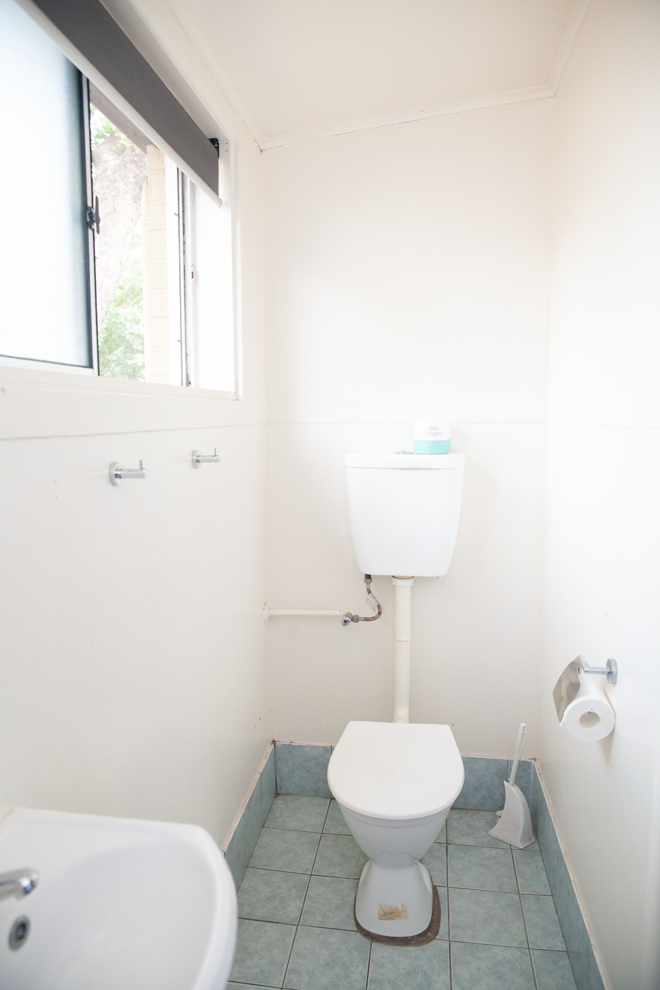 A small bathroom with a toilet, sink, and window.