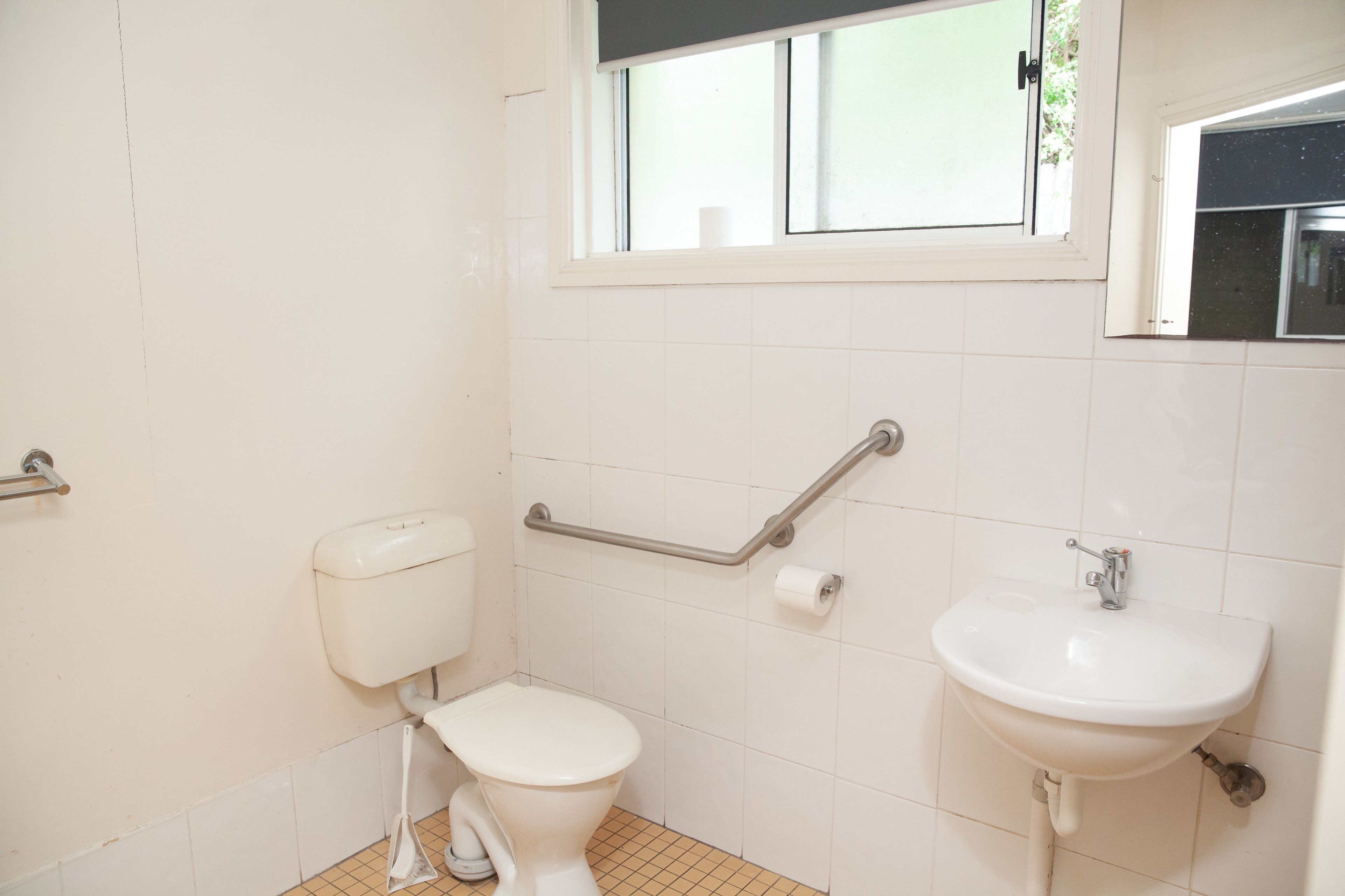 A bathroom with a toilet, a sink, and a window.
