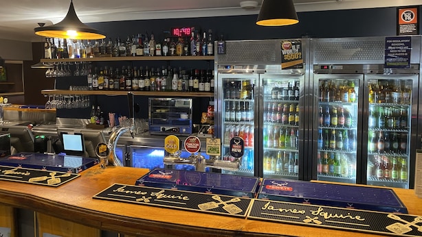 A bar area with a counter, multiple taps, and a digital clock displaying 10:40. - Royal Hotel Singleton (Singleton)