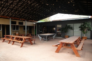 An outdoor patio area with picnic tables, a pool table, and potted plants.