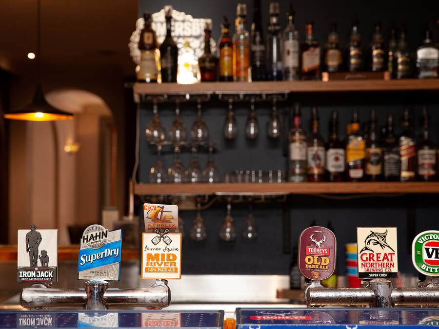 Eine Bar mit verschiedenen Zapfhähnen und einer Flaschenregal mit Spirituosen.
