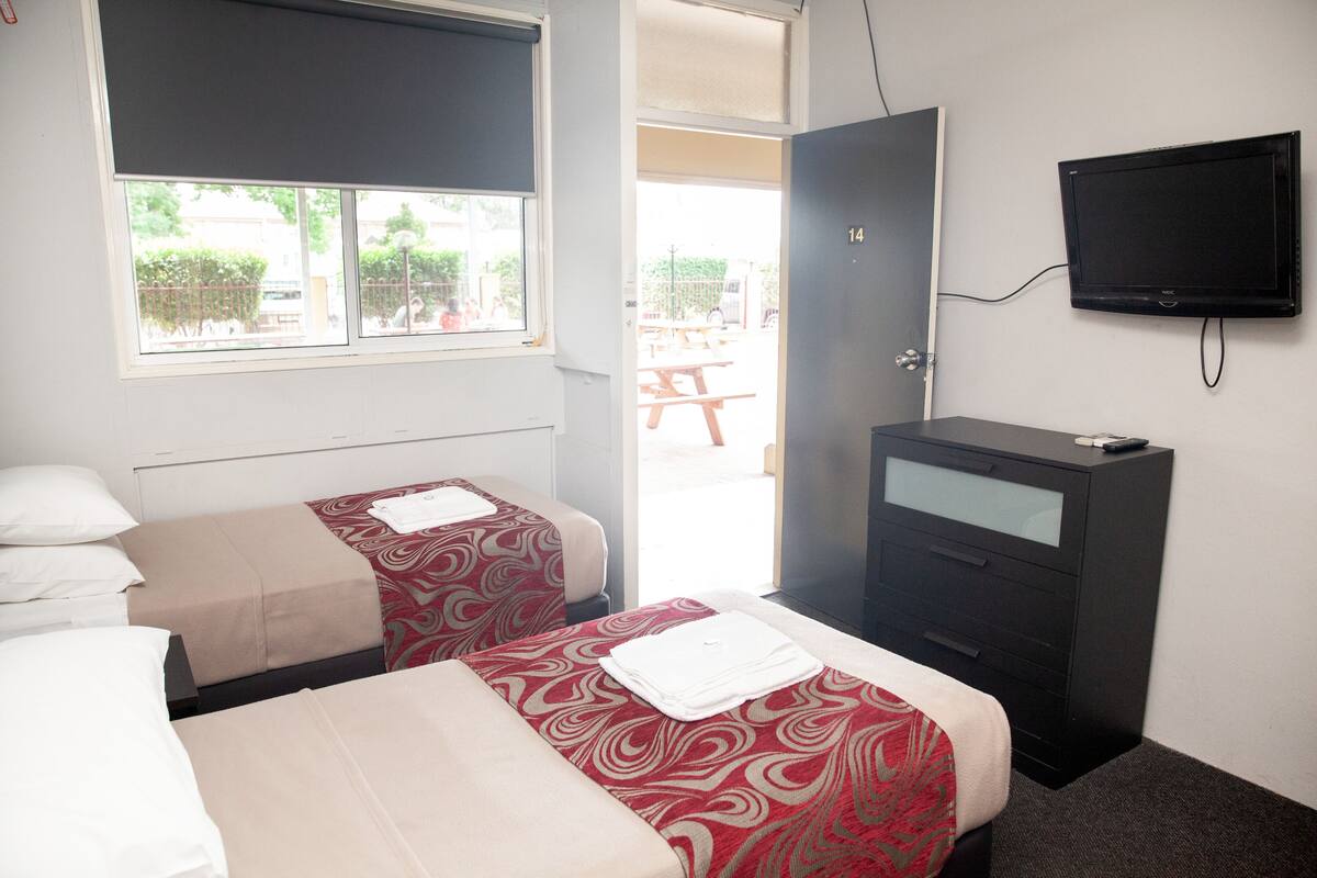 A hotel room with two beds, a TV, and a desk.