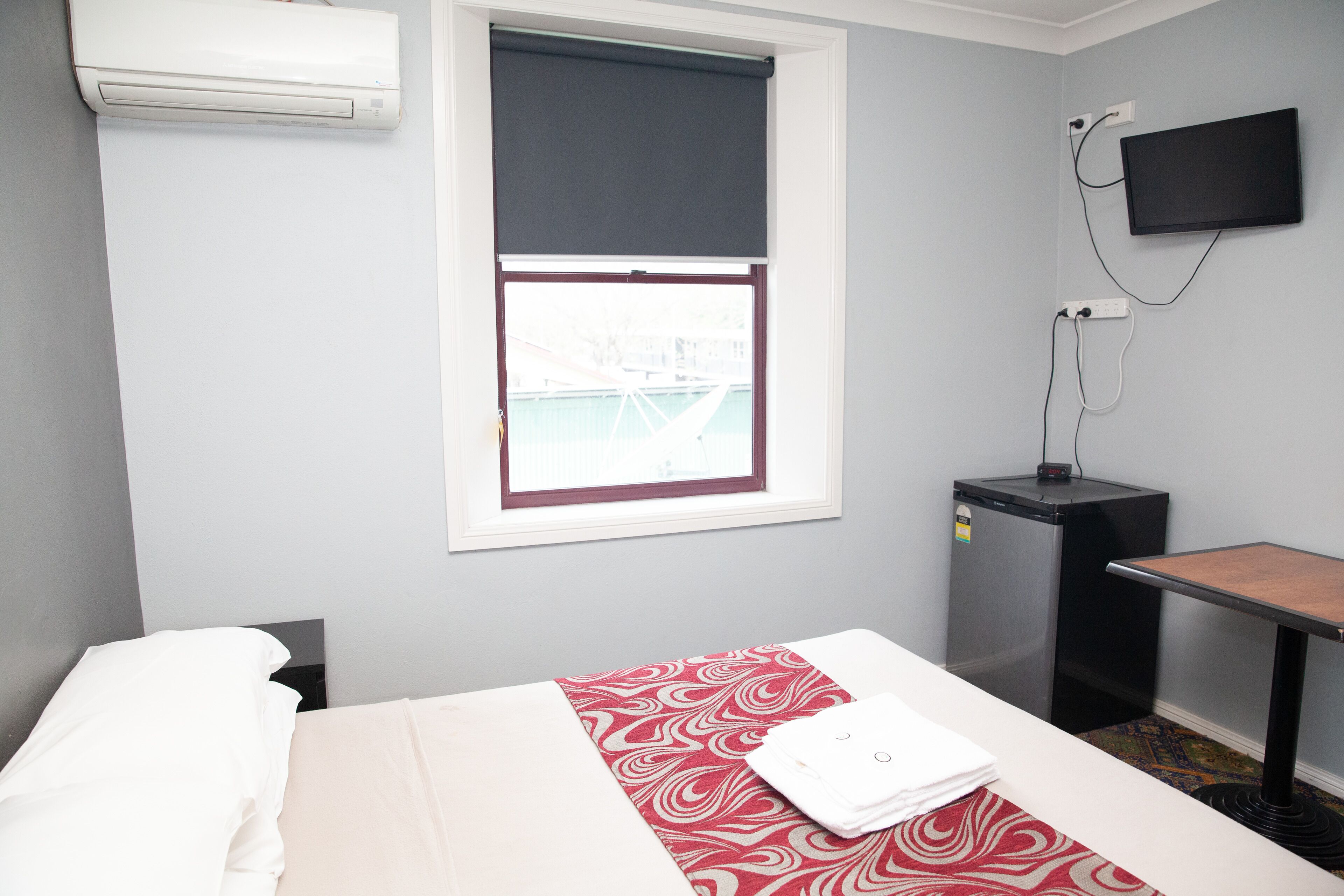 A hotel room with a bed, a small table, a TV, and a window with a view.