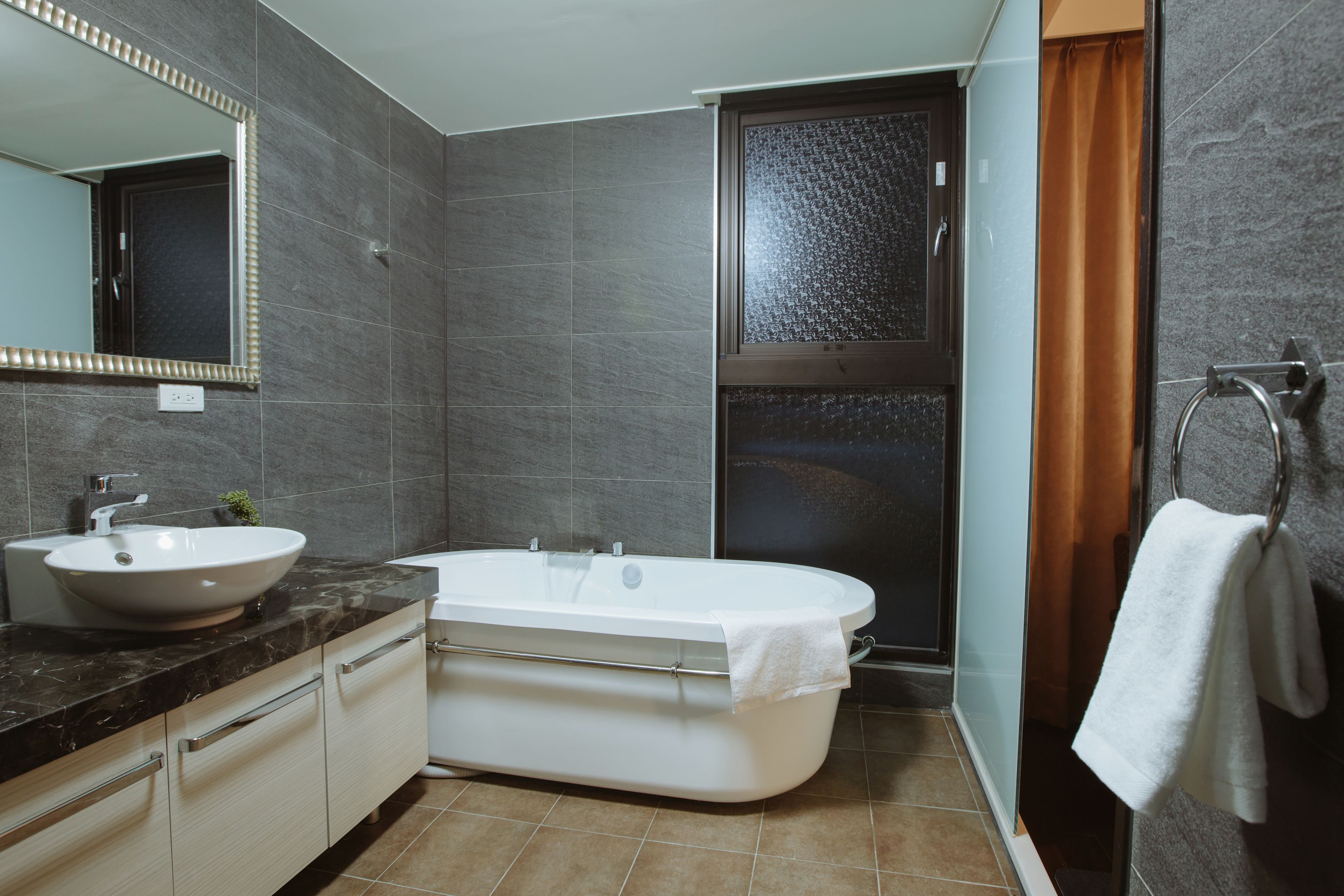 A modern bathroom with a bathtub, sink, and shower.