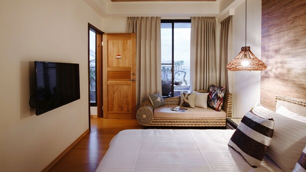 A hotel room with a large bed, a television, a wicker sofa, and a balcony with curtains. - Grand Allevia Villa (Wujie)