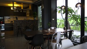 A modern kitchen with a dining area, large windows, and a ceiling fan. - Grand Allevia Villa (Wujie)