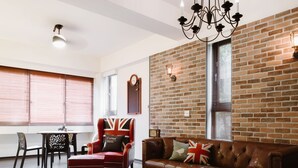 A modern living room with a brick wall, leather sofa, and a chandelier. - Grand Allevia Villa (Wujie)
