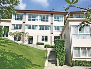 A modern multi-story building with large windows, a staircase, and a well-maintained lawn. - Royal Lee Resort & Spa (Sa Khu)