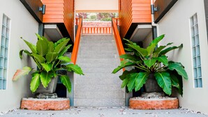 A narrow pathway leading to a building entrance with a wooden gate, flanked by large potted plants. - Royal Lee Resort & Spa (Sa Khu)