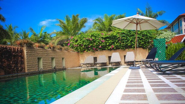 A swimming pool with clear water, surrounded by lounge chairs and an umbrella. - Royal Lee Resort & Spa (Sa Khu)