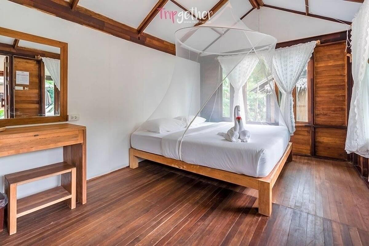 Uma cama de madeira com dossel, um banco de madeira e uma escrivaninha de madeira com espelho.