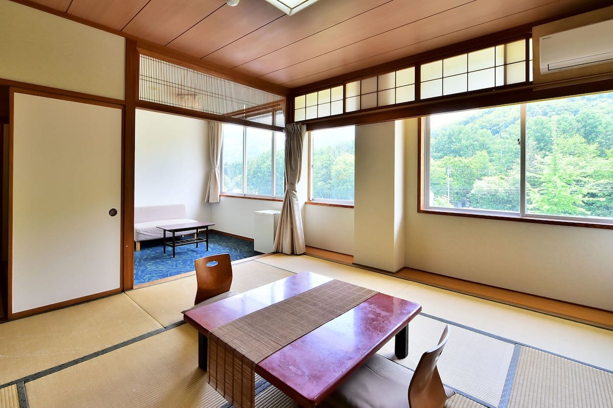 A traditional Japanese room with tatami flooring, a low table, and sliding doors.