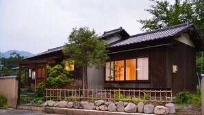 A traditional Japanese house with a wooden exterior, a tiled roof, and a wooden fence in front.