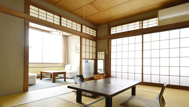 A traditional Japanese room with tatami flooring, a low table, a cushioned bench, and sliding doors.