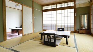 A traditional Japanese room with tatami flooring, a low table, a chair, and sliding doors.