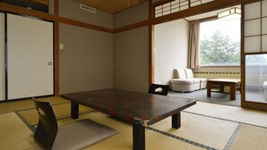 A traditional Japanese room with tatami flooring, a low table, cushions, and sliding doors.