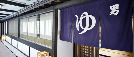 A hallway with a glass partition, a purple banner with white text, and a wooden door with a grid pattern.