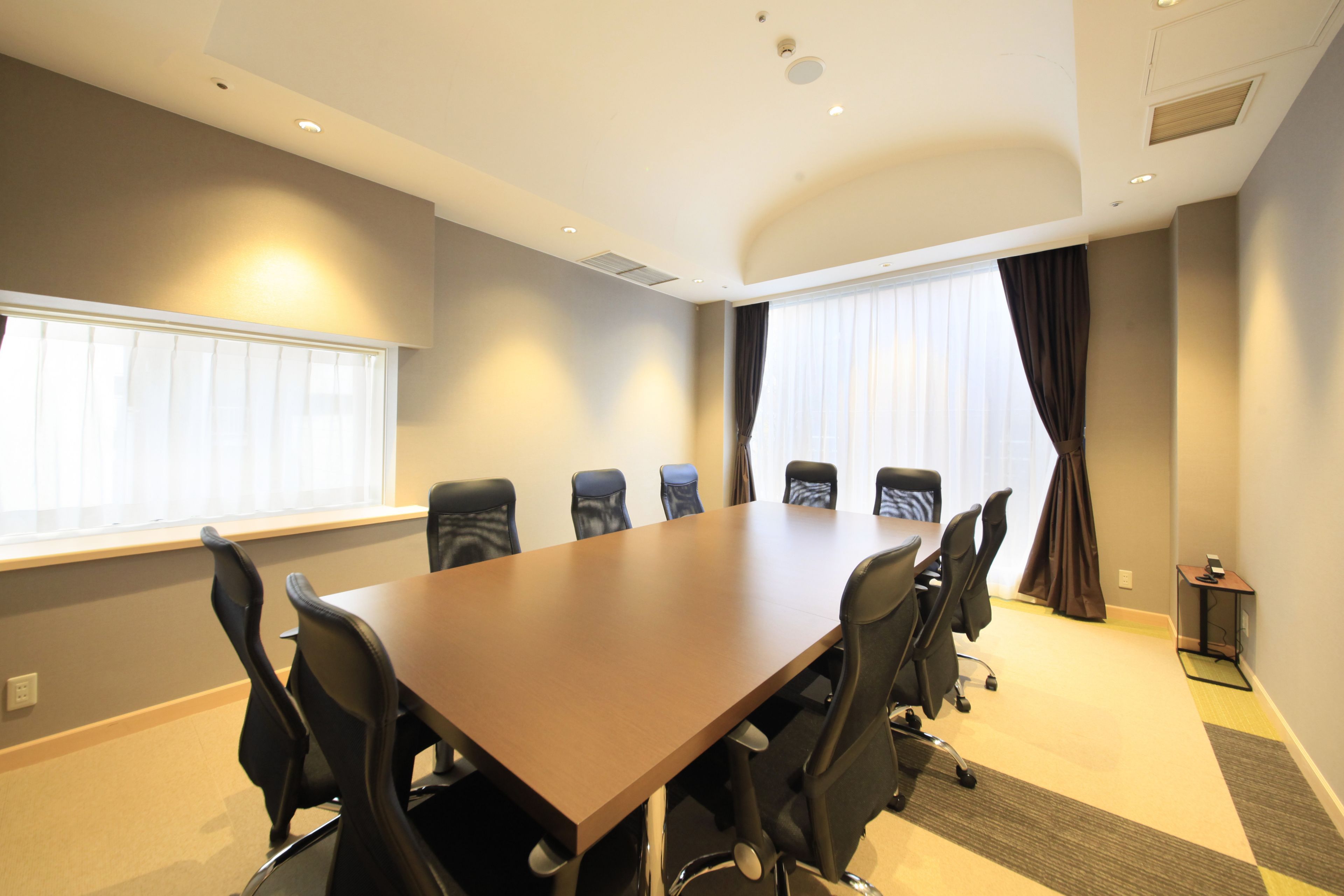 A conference room with a long table, six chairs, and a small side table.