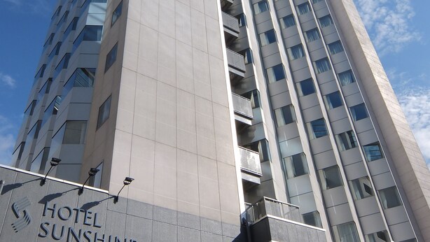 Un edificio de hotel alto con diseño moderno, que presenta varios balcones y un cielo despejado al fondo.