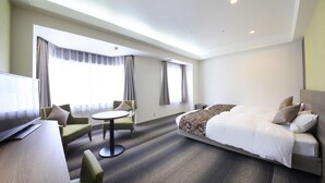 Una habitación de hotel con una cama, televisión, escritorio y una silla.