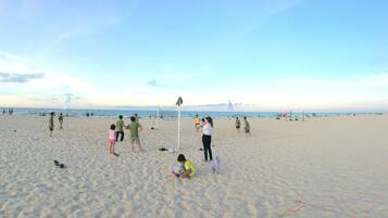 A beach with people playing and walking.