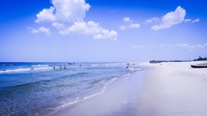 Ein Strand mit blauem Himmel und ruhigem Wasser.