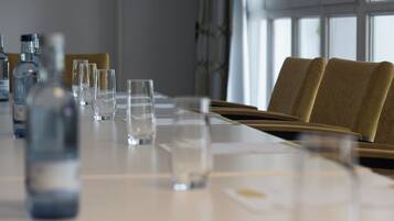 Una mesa de conferencias con sillas, vasos transparentes y botellas, probablemente para una reunión o evento.