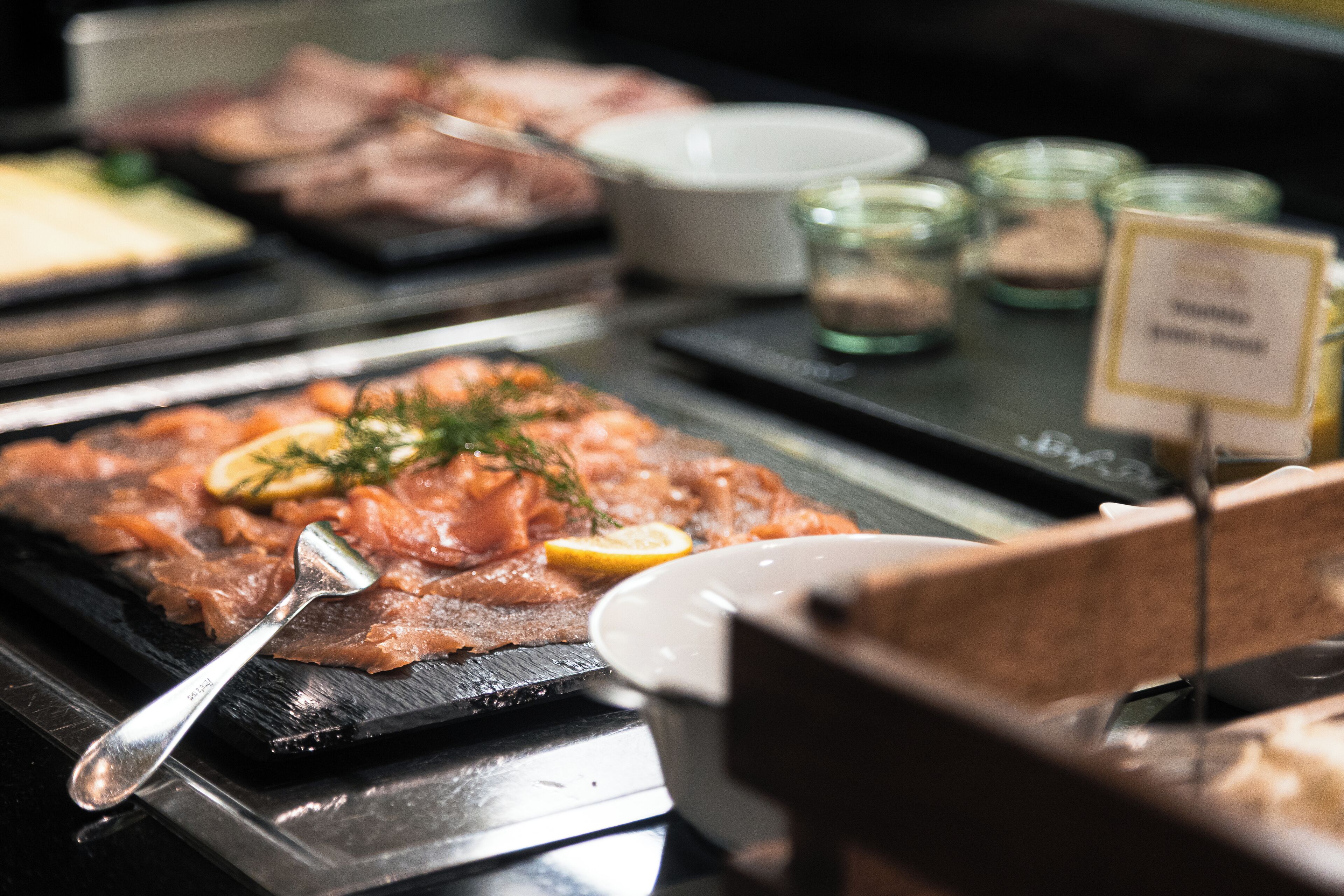 A buffet with various dishes, including salmon and other meats, arranged on a black tray.