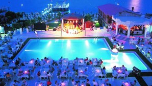 Zona de piscina con asientos al aire libre y un escenario para presentaciones.