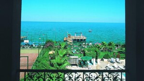 Vista de un complejo turístico frente a la playa, con área de piscina, sillones de descanso y un muelle que se adentra en el mar.