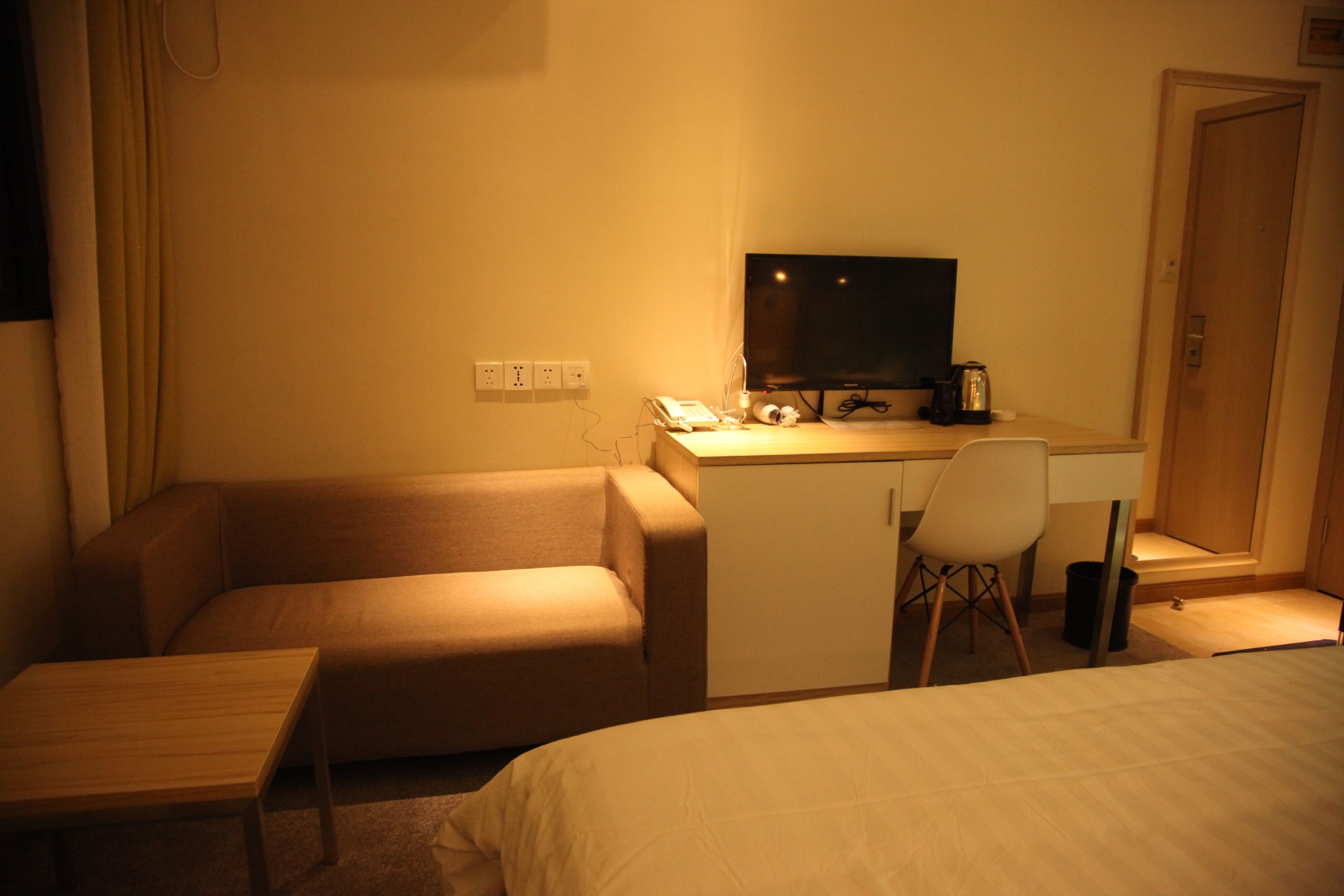 Une chambre d’hôtel comprenant un lit, un bureau avec un ordinateur, une chaise, une petite table et une armoire.