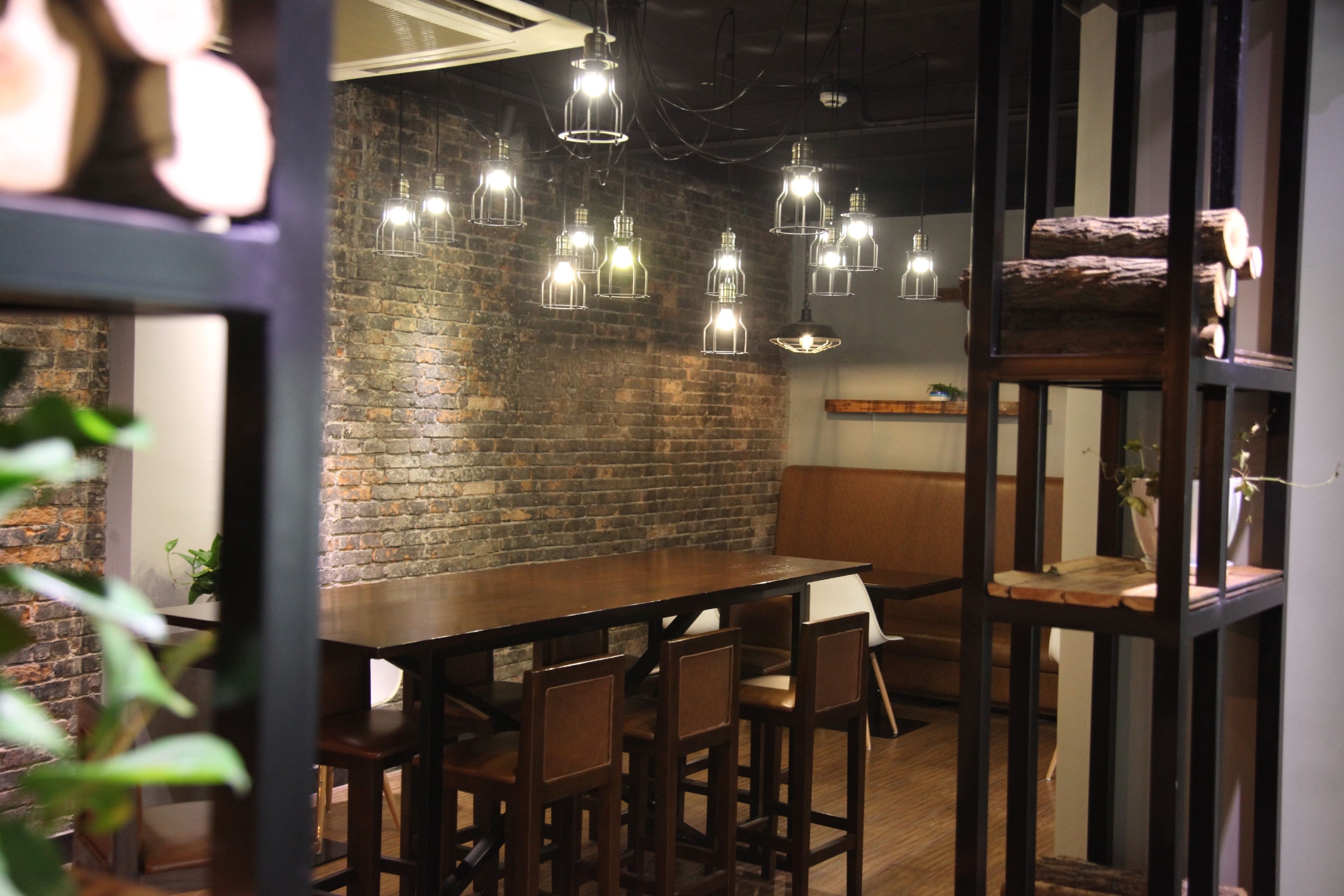Un restaurante con pared de ladrillo, lámparas colgantes, mesas y sillas de madera.
