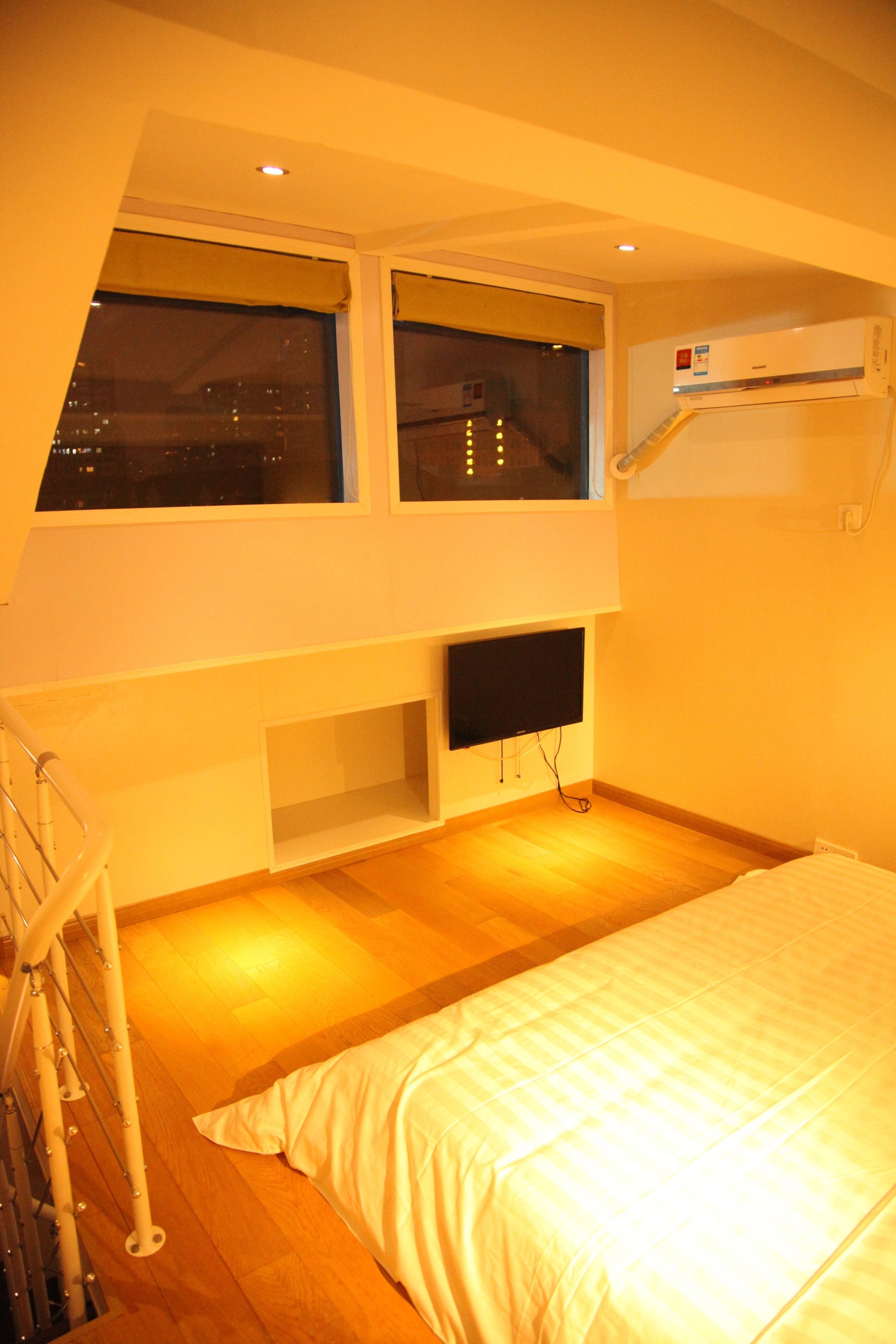 Un dormitorio con cama, televisor y ventana.