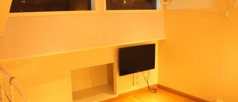Un dormitorio con cama, televisor y ventana.