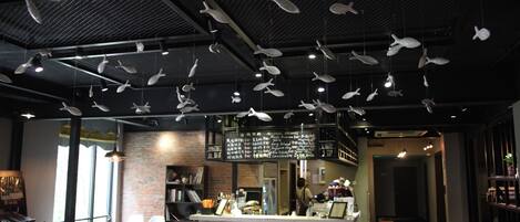 A restaurant interior with hanging fish decorations, a bar area, and a brick wall.