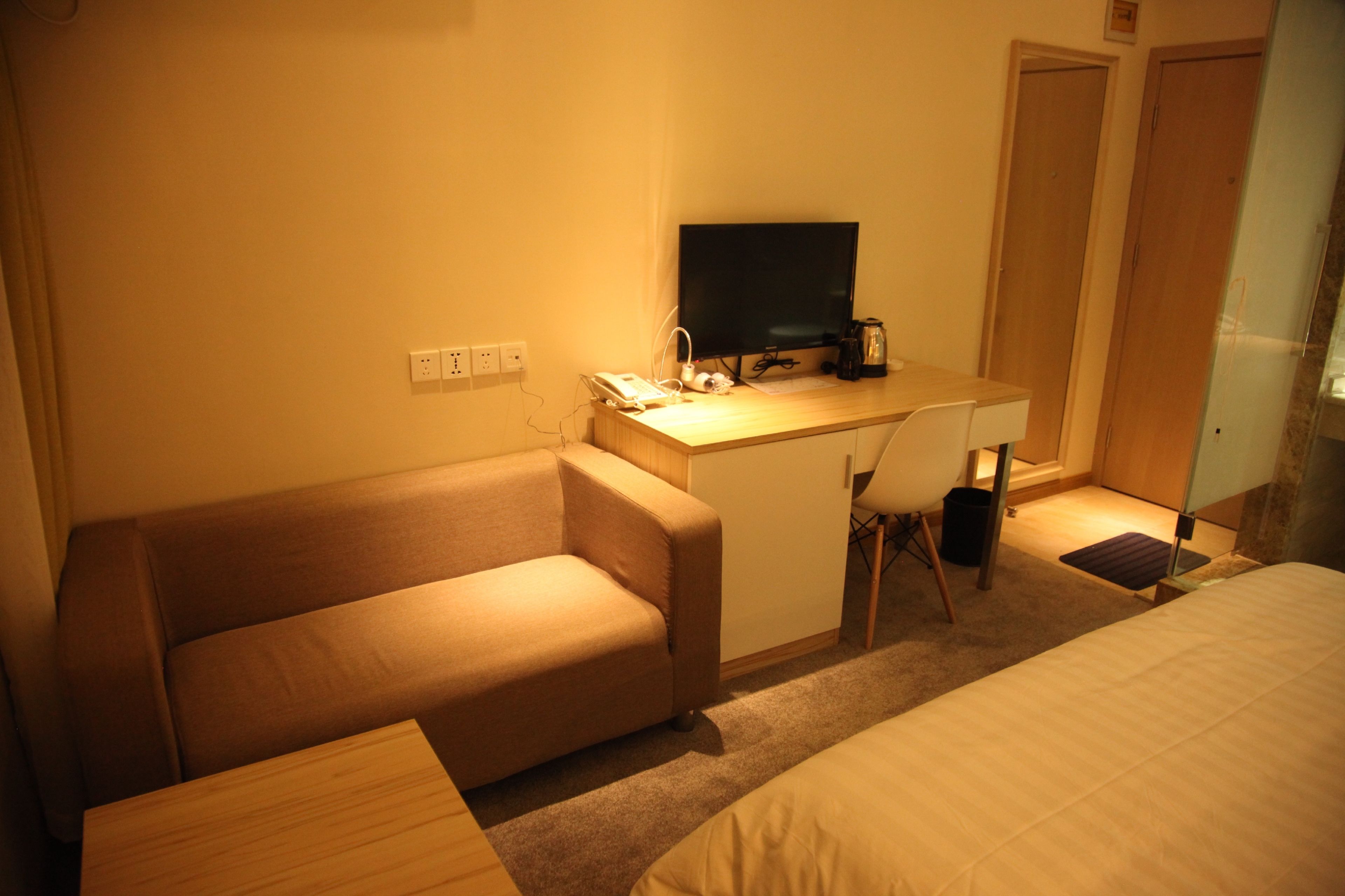 Une chambre d’hôtel équipée d’un lit, d’un canapé, d’un bureau avec un ordinateur et d’une machine à café.