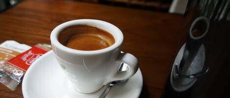 Une tasse de café blanche, posée sur une soucoupe avec une cuillère, sur une table en bois.