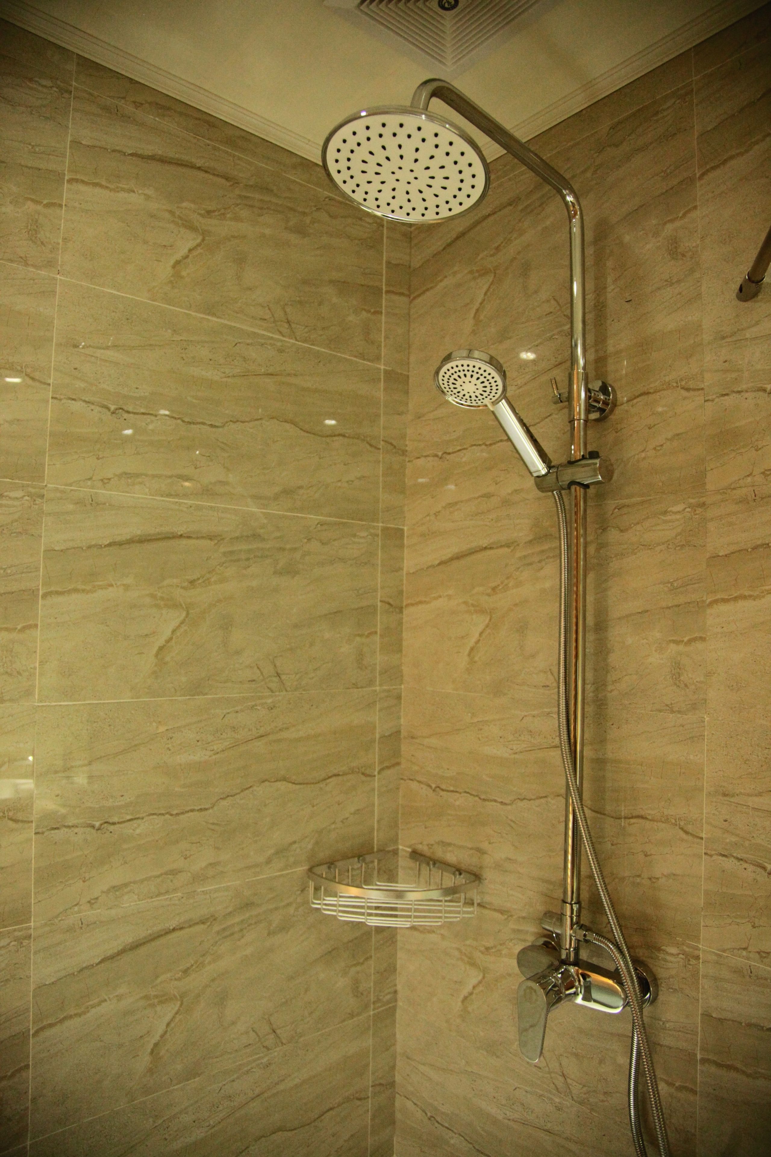 Een douche met een handdouche en een kraan aan de muur.