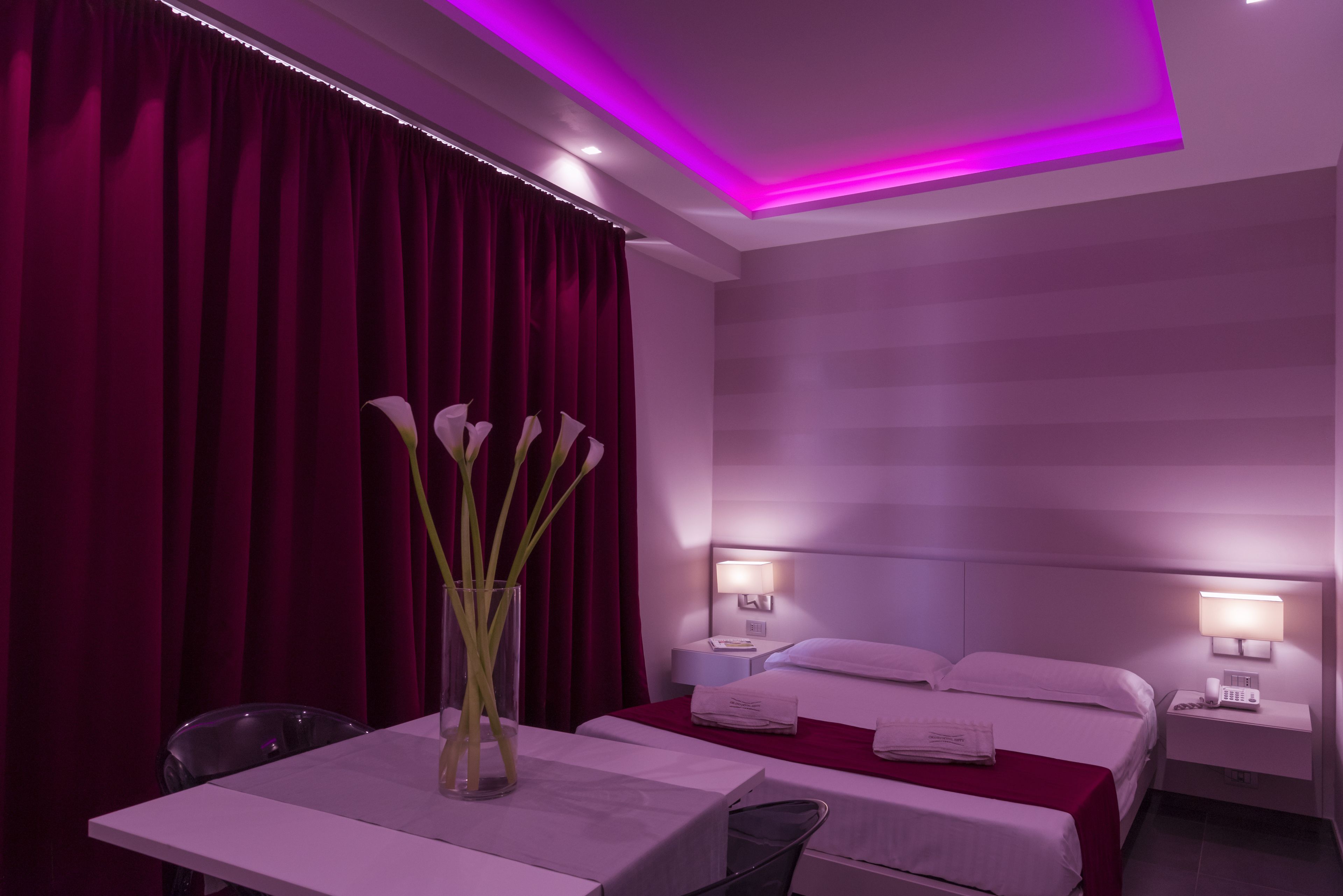 A hotel room with a bed, bedside tables, a desk, and a chair.
