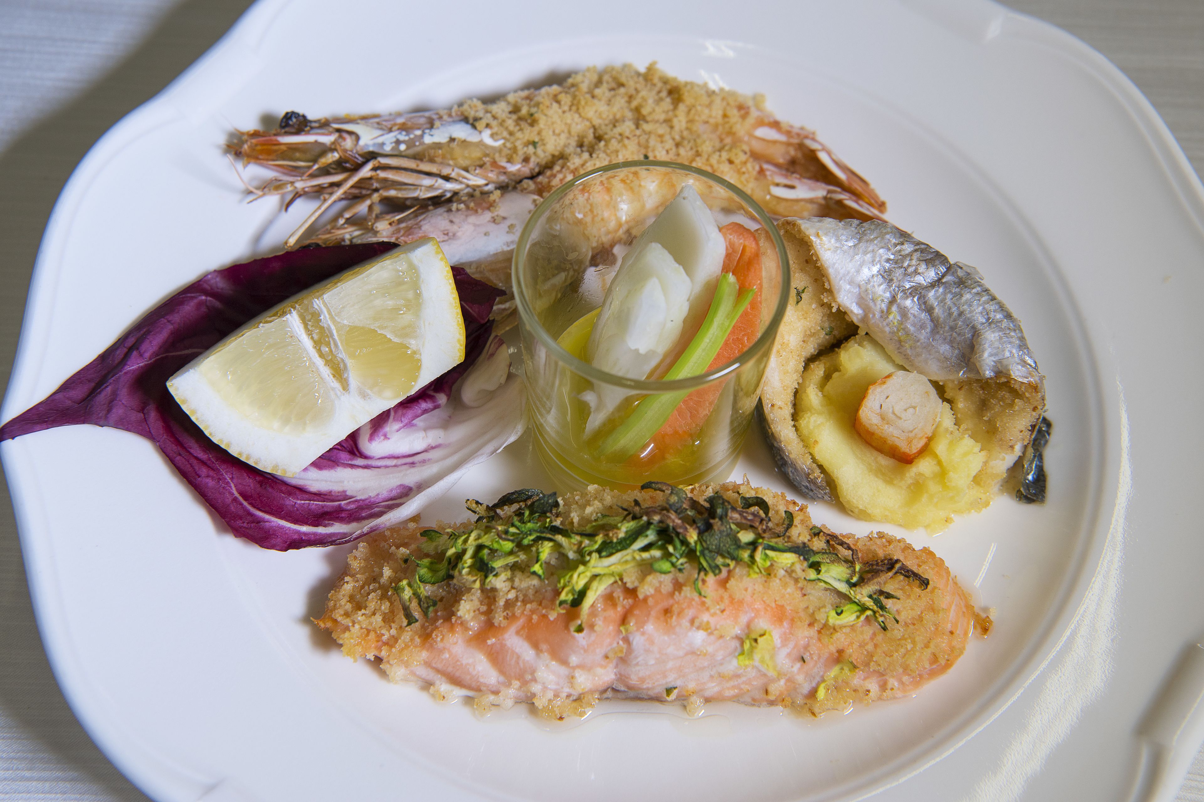 A plate with various seafood dishes including salmon, shrimp, and a fish with a crispy coating.