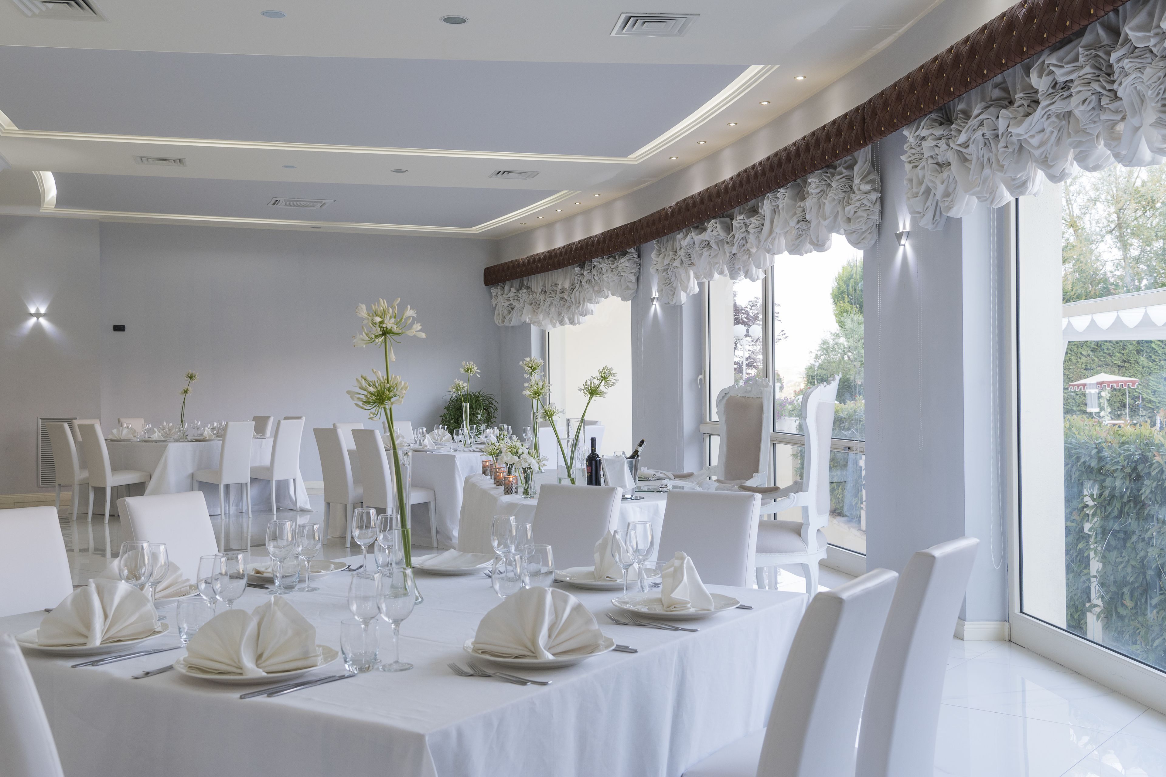 Un espace repas avec une décoration de table blanche, comprenant des assiettes, des verres et des couverts.
